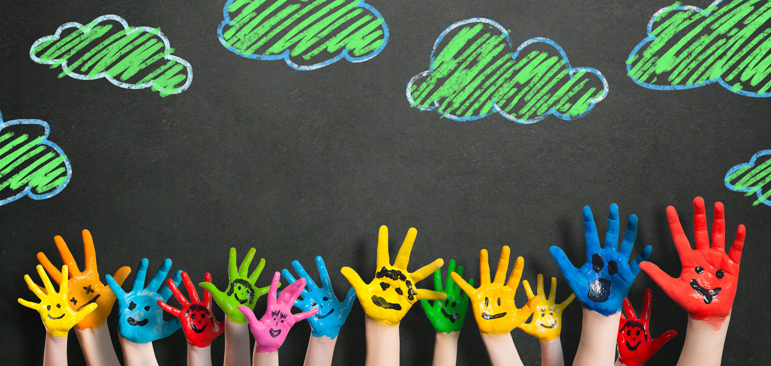 painted kids hands in front of a blackboard